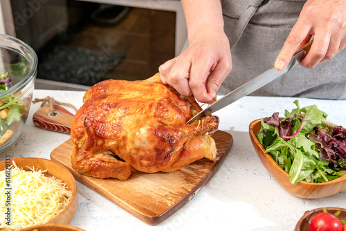 Woman cuts into a roast chicken for making Caesar salad.