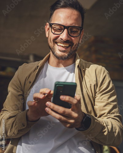Фотография One adult man in front house in day use smart phone video call or sms
