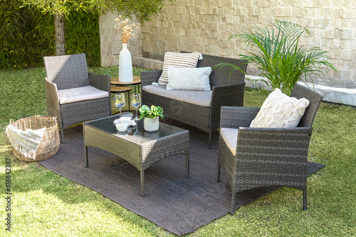 Fototapete A modern outdoor rattan furniture living room set in a lush green grassy landsca