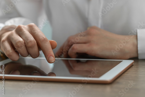 Closeup view of woman using modern tablet at table
