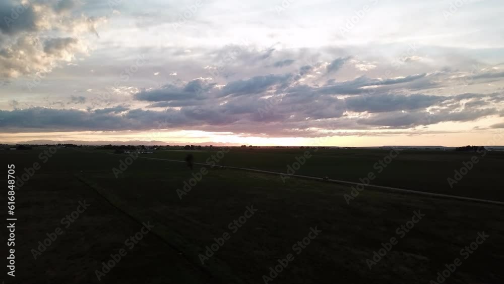 Aerial Shot Of Car On Road Amidst Plants Against Cloudy Sky, Drone Flying Forward Over Landscape At Dusk - Billings, Montana Aerial Shot Of Car On Road Amidst Plants Against Cloudy Sky, Drone Flying Forward Over Landscape At Dusk - Billings, Montana