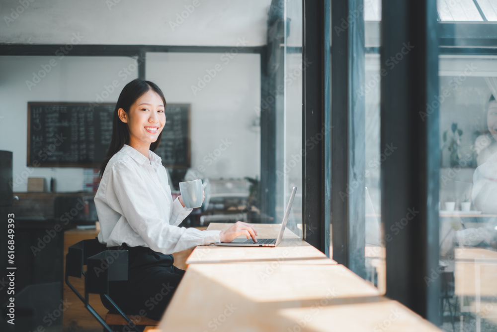 Portrait of young business woman working on laptop in office, Woman holding coffee cup in office. Portrait of young business woman working on laptop in office, Woman holding coffee cup in office.