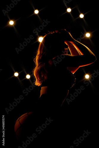 Contour of a beautiful dancer who poses in the light of the lights. Black linen with spikes. atmospheric light. Party concept, nightclub