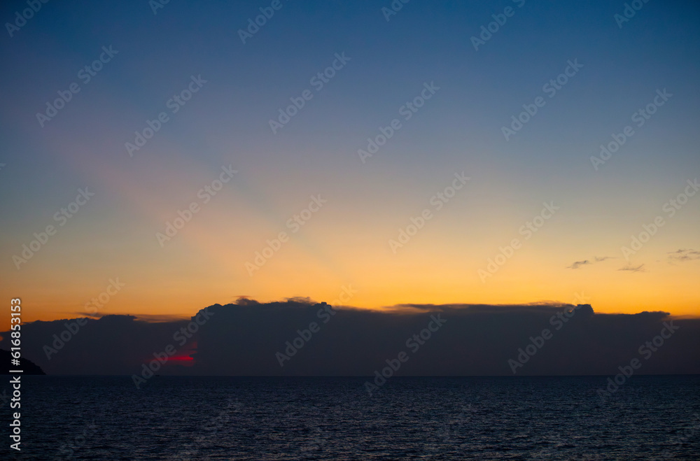 The sky and the sea in the evening near the sun will set. The golden yellow light against the water was a beautiful moment. sometimes saw mountain shadows interspersed The sky and the sea in the evening near the sun will set. The golden yellow light against the water was a beautiful moment. sometimes saw mountain shadows interspersed