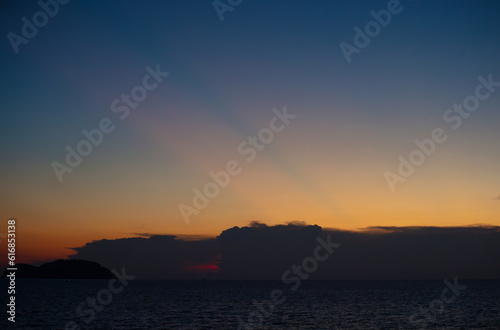 The sky and the sea in the evening near the sun will set. The golden yellow light against the water was a beautiful moment. sometimes saw mountain shadows interspersed