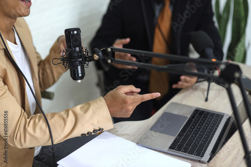 Close up of young Asian man radio hosts interviewing a businessman guest in a studio while recording podcast for online show in studio together
