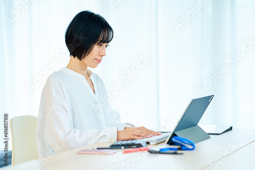 部屋でノートパソコンを使う女性