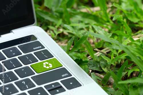 environmental technology concept.green recycle button on a black keyboard on green grass. Recycle zero waste ecology saving technology. Circular technology for digital and environmental sustainability