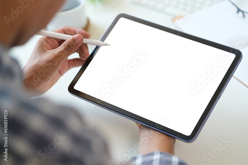 View over businessman shoulder hands using digital tablet at white working desk.