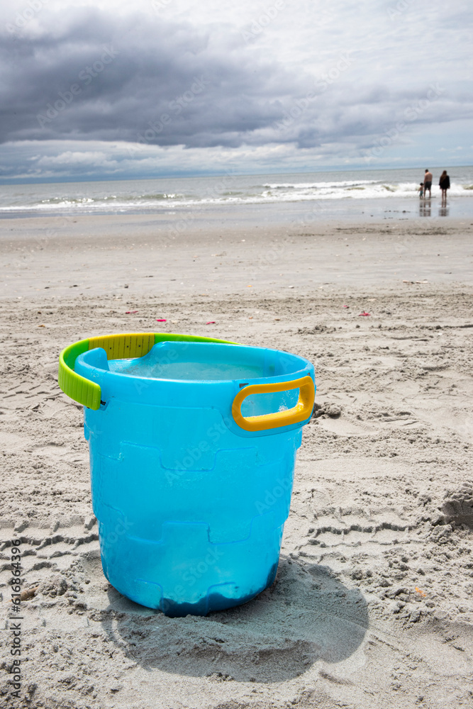 abandoned blue bucket on the sand at the beach, not being played with, copy space abandoned blue bucket on the sand at the beach, not being played with, copy space