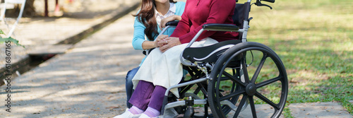 Family relationship Asian senior woman in wheelchair with happy daughter holding caregiver for a hand while spending time together