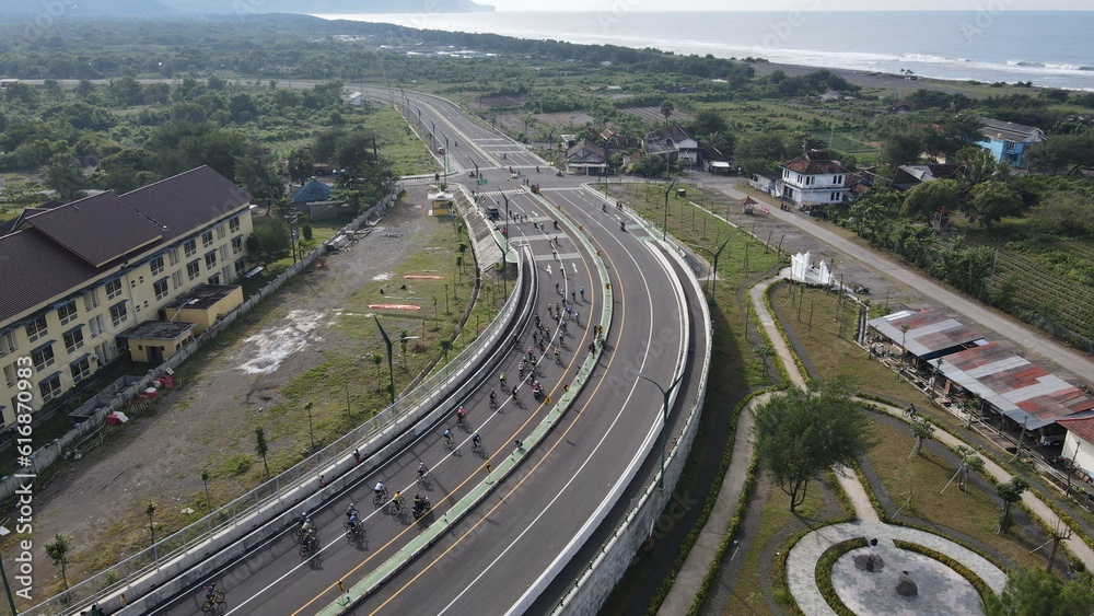 Aerial view of a wide road near the southern coast of Yogyakarta, passed by road bikers