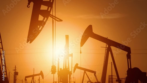 The sun rises behind a large oil field in California.