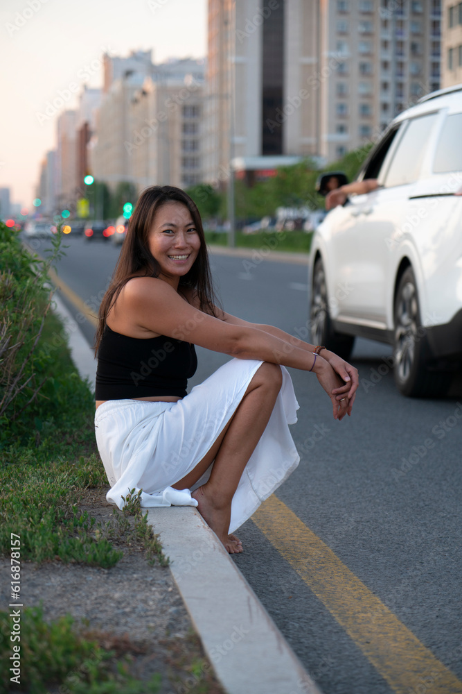 Asian girl sits on the side of the road.