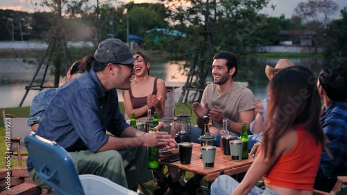 Group of friends are sitting and clap hands singsong in camping near lake. photo