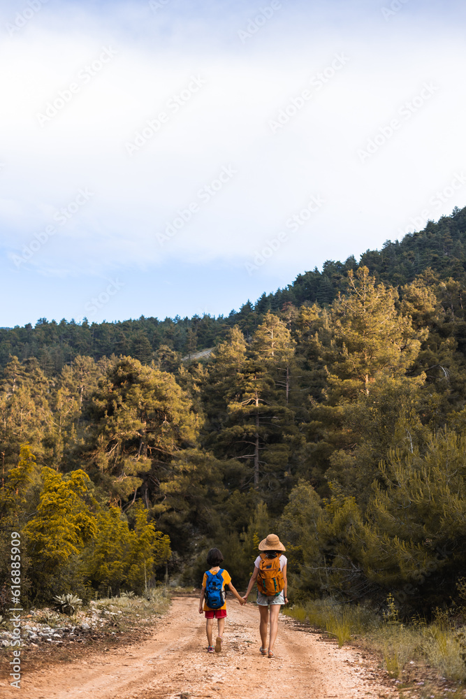 A child with mom walks along a forest path