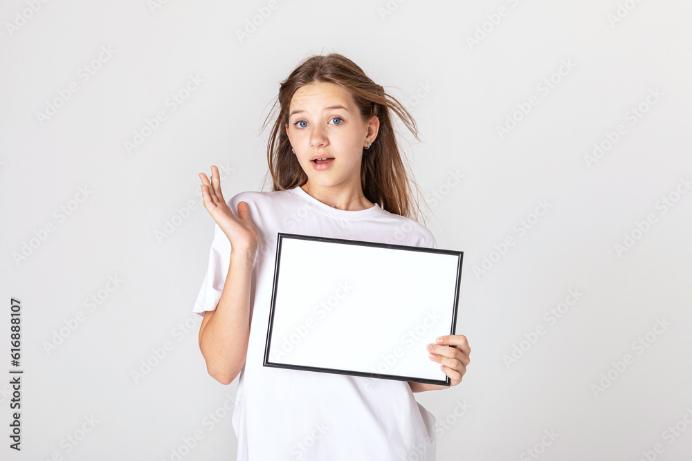 White banner .Teenager girl hold white blank paper. Young surprised woman show blank board. Close up female model portrait on white background. White banner .Teenager girl hold white blank paper. Young surprised woman show blank board. Close up female model portrait on white background.