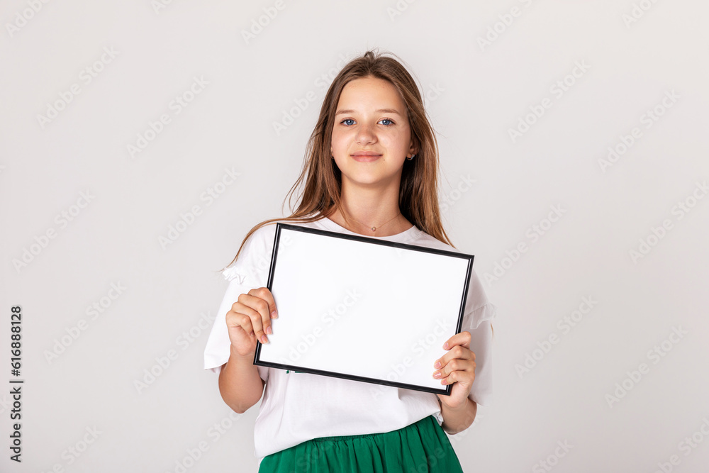 White banner .Teenager girl hold white blank paper. Young smiling woman show blank board. Close up female model portrait on white background. White banner .Teenager girl hold white blank paper. Young smiling woman show blank board. Close up female model portrait on white background.