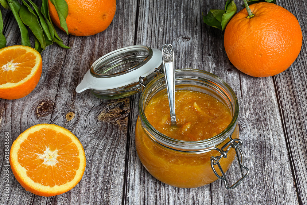 Delicious homemade orange marmalade in an open glass jar with teaspoon inside. Homemade dessert on a wooden table. Top view, white background. Delicious homemade orange marmalade in an open glass jar with teaspoon inside. Homemade dessert on a wooden table. Top view, white background.