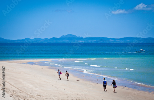 Two couples walk on an ideal beach on Keppel Island, Queensland, Australia. Sun-soaked sand beside the turquoise ocean at the start of the Great Barrier Reef. photo