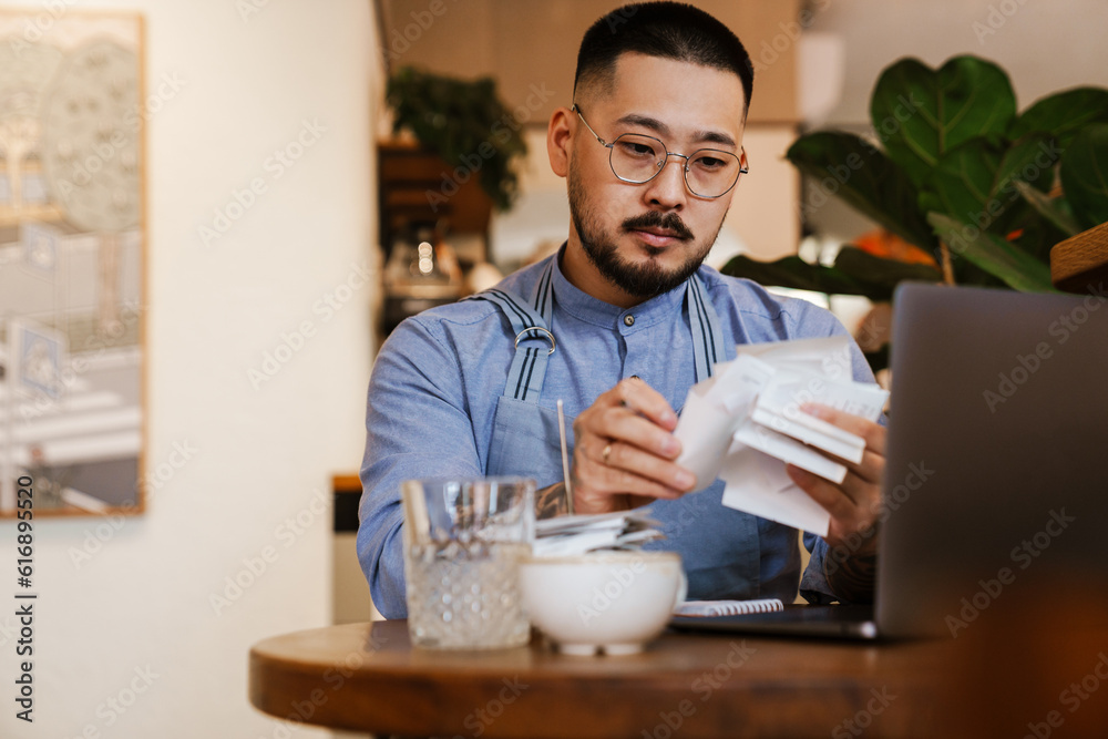 Business owner working with financial bills and calculates profit while sitting in cafe Business owner working with financial bills and calculates profit while sitting in cafe