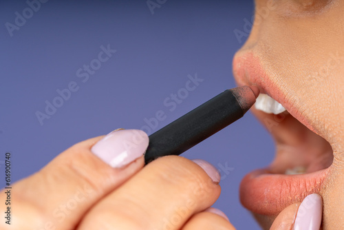 Lining young woman's lips with lipstick