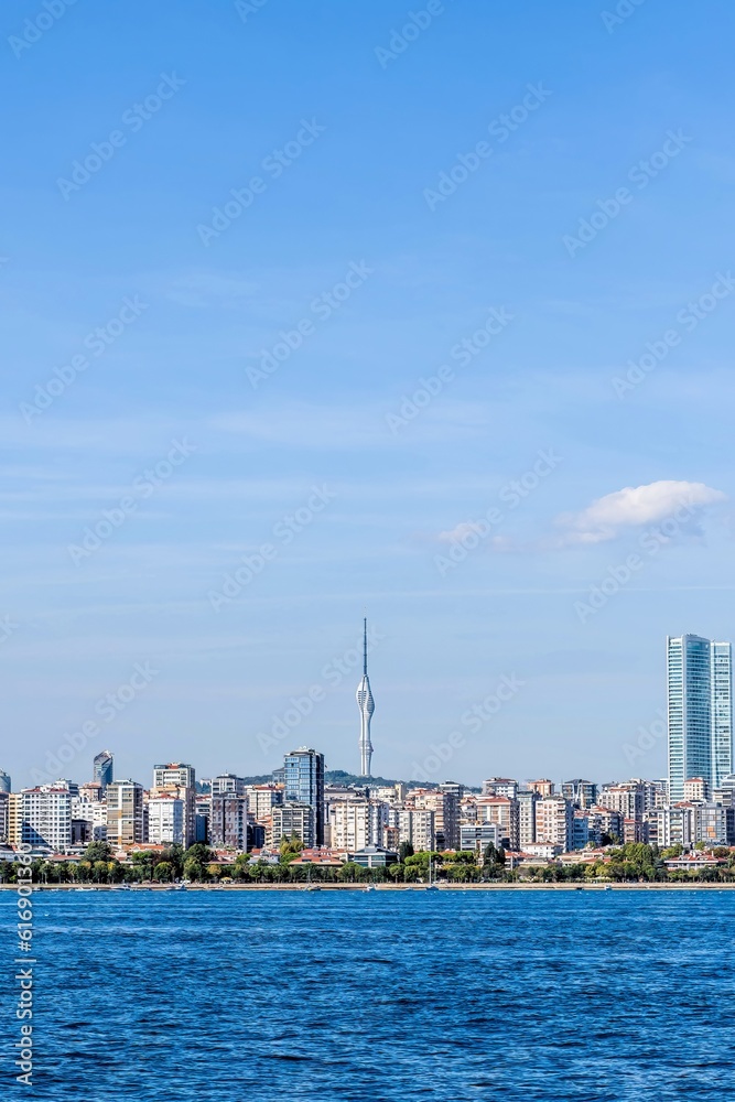 Coastal landscape of city buildings with communication tower in background.