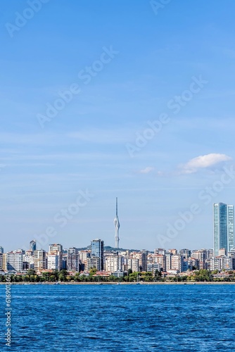Coastal landscape of city buildings with communication tower in background.