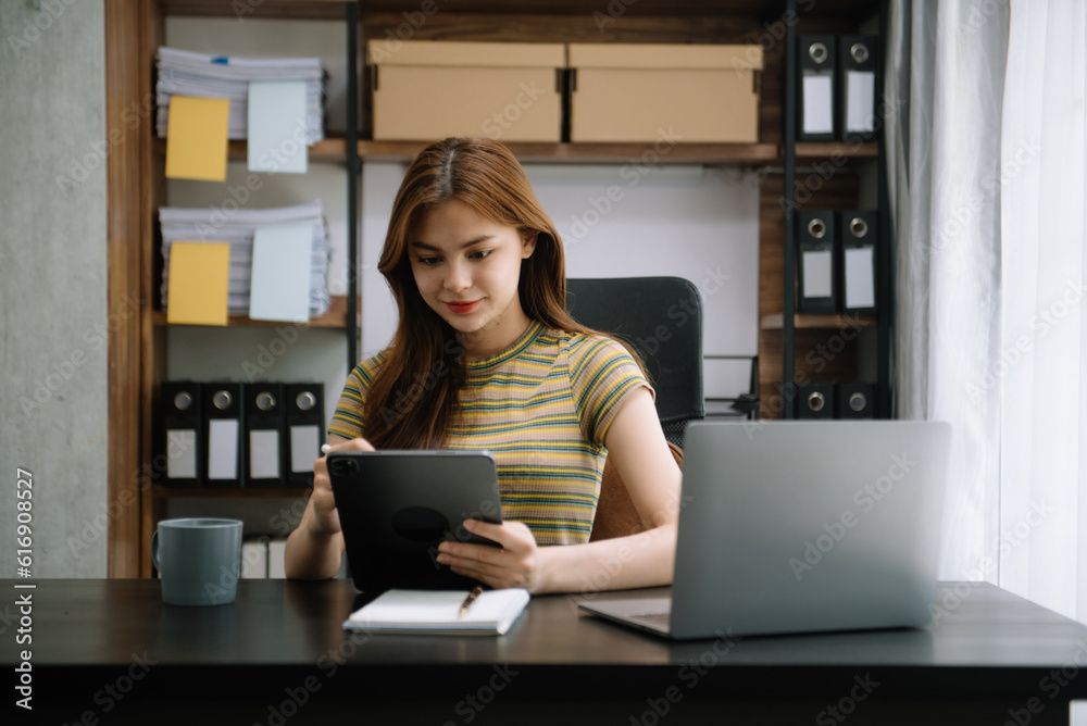 Young beautiful woman typing on tablet and laptop while sitting at the working wooden table office. Young beautiful woman typing on tablet and laptop while sitting at the working wooden table office.