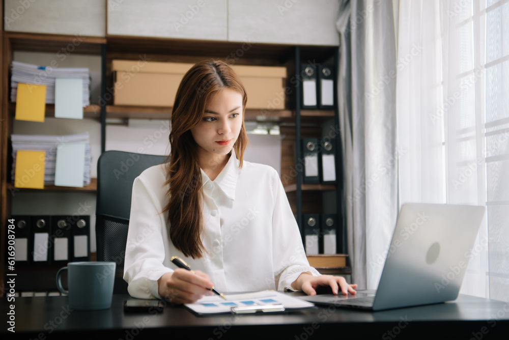 Young beautiful woman typing on tablet and laptop while sitting at the working wooden table office. Young beautiful woman typing on tablet and laptop while sitting at the working wooden table office.