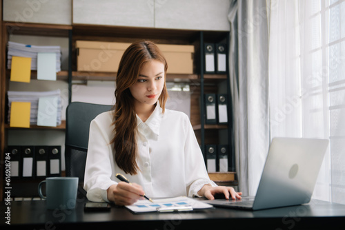 Young beautiful woman typing on tablet and laptop while sitting at the working wooden table office.