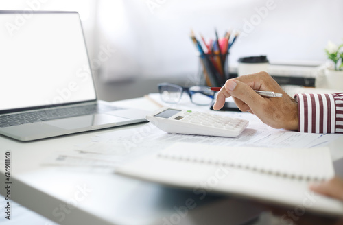accountant working on desk with computer laptop and using calculator for calculate finance report or tax in office, Planning financial and accounting concept