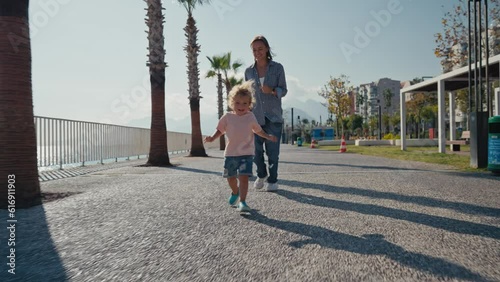 Slow motion Happy caucasian little boy running infront of her mother at the summer seaside. Mom and son happy time in the nature. Woman chasing her son playing outdoor. High quality 4k footage photo