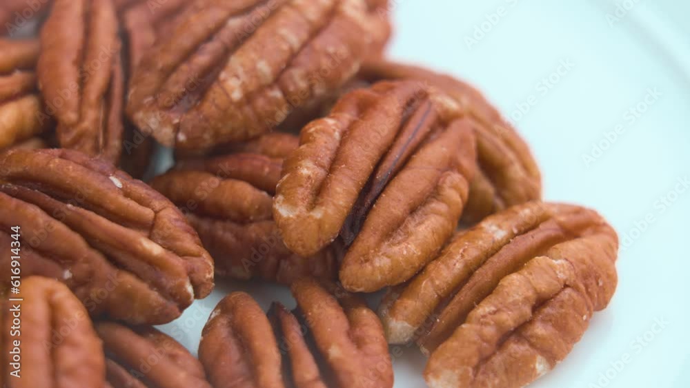 Raw organic pecan nuts on a white surface of kitchen plate. Rotation Raw organic pecan nuts on a white surface of kitchen plate. Rotation