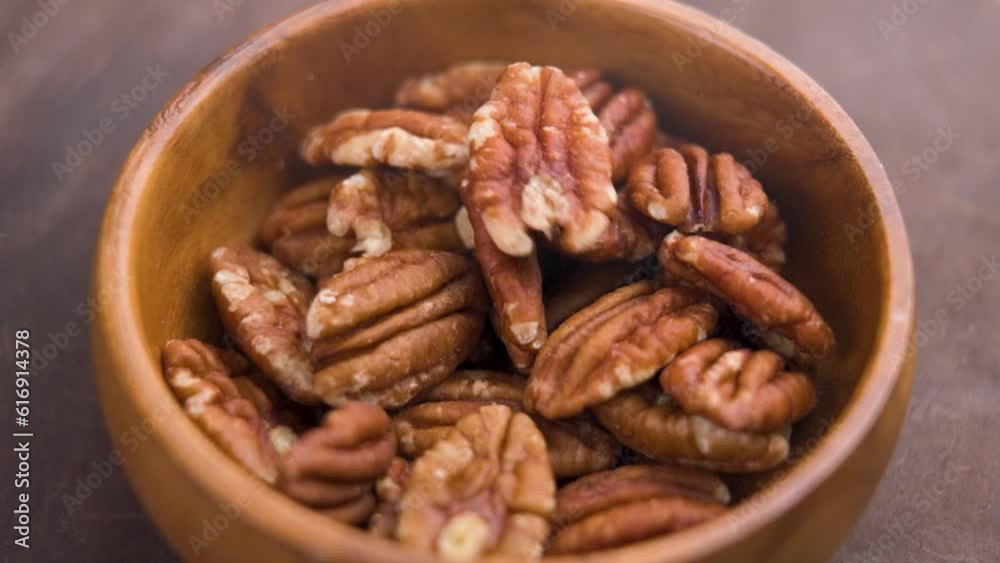 Dry natural pecans falling into a rustic wooden bowl. Diet dried healthy nut Dry natural pecans falling into a rustic wooden bowl. Diet dried healthy nut