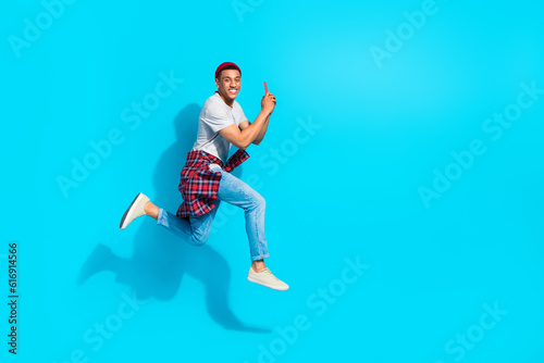 Full body profile photo of excited handsome guy jumping rush empty space use smart phone isolated on blue color background