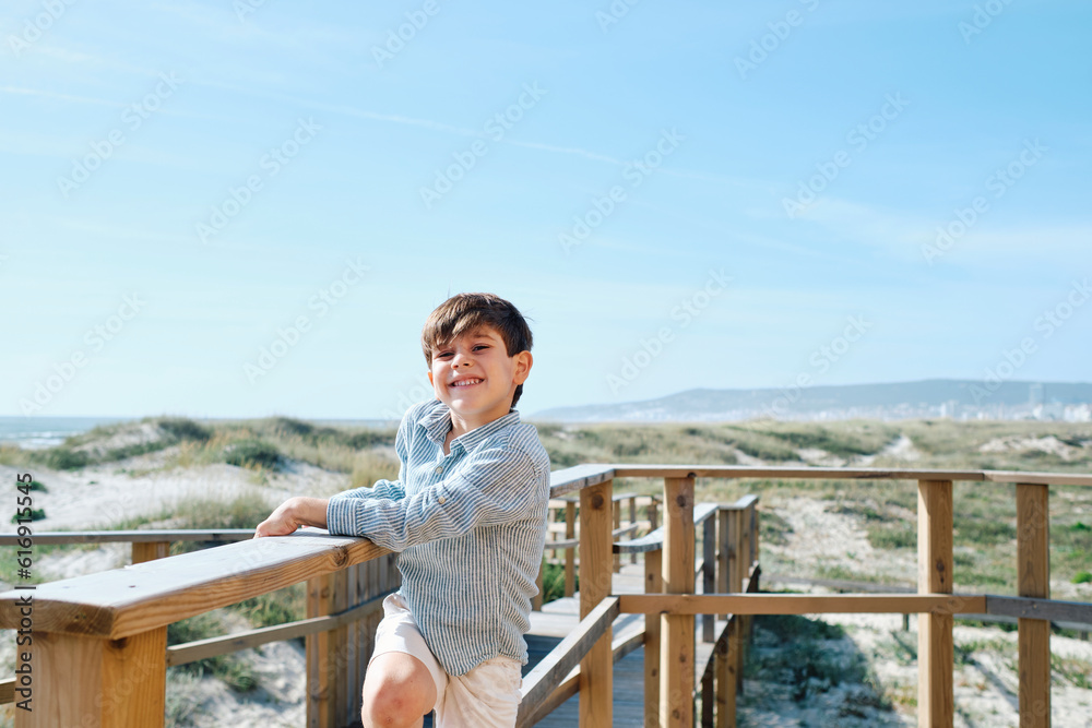 Happy boy standing by wooden railing on sunny day Happy boy standing by wooden railing on sunny day
