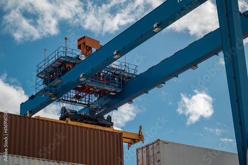 Craine or container hoist at a port of Belfast, Northern ireland. Visible container spreader, blue beam with winch and two containers below. photo