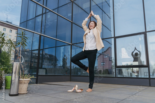 Businesswoman practicing tree pose outside office building photo