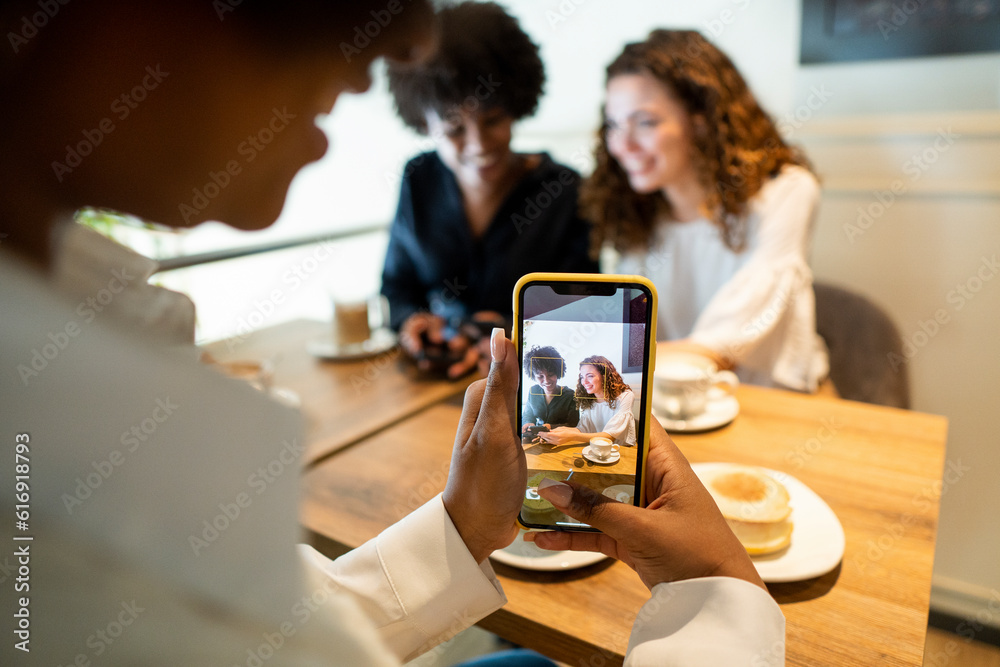 Woman photographing friends through smart phone Woman photographing friends through smart phone