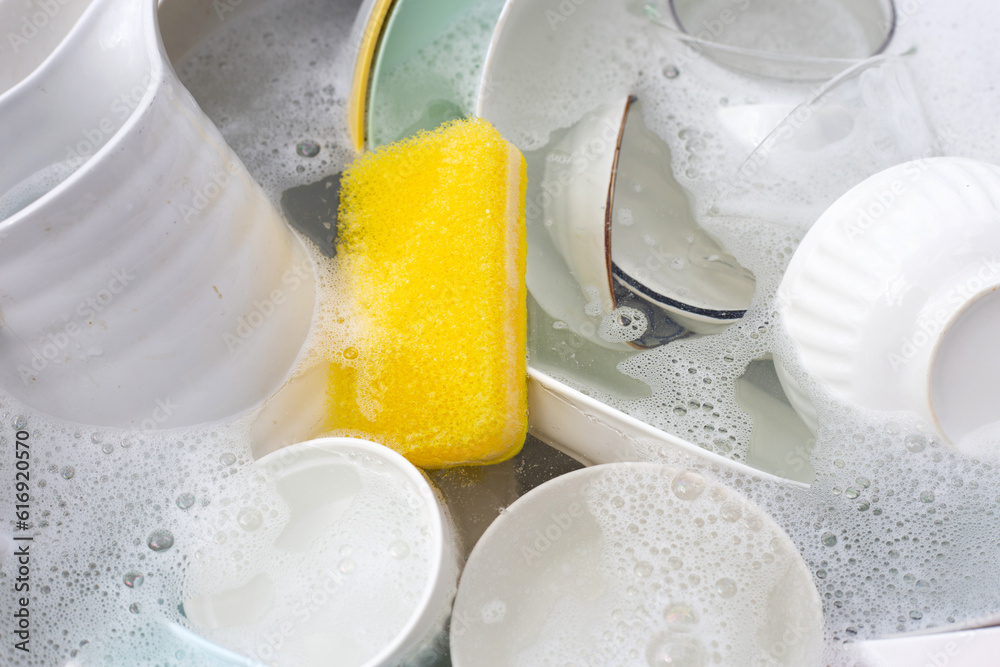 Dishes and bowls in water and bubbles of dishwashing liquid. Kitchen work Dishes and bowls in water and bubbles of dishwashing liquid. Kitchen work
