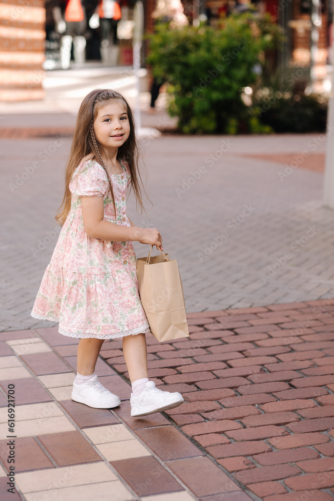 Back view of cute little girl on shopping. Portrait of adorable kid with shopping bags