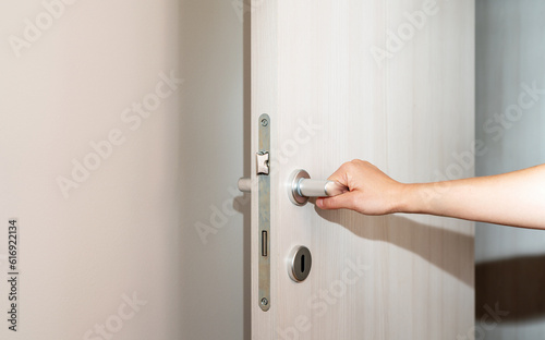 Female hand on door handle, opening the door.