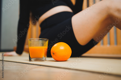 A glass of freshly squeezed orange juice on the background of a young woman. Useful juice for a woman's body. Vitamin citrus fresh