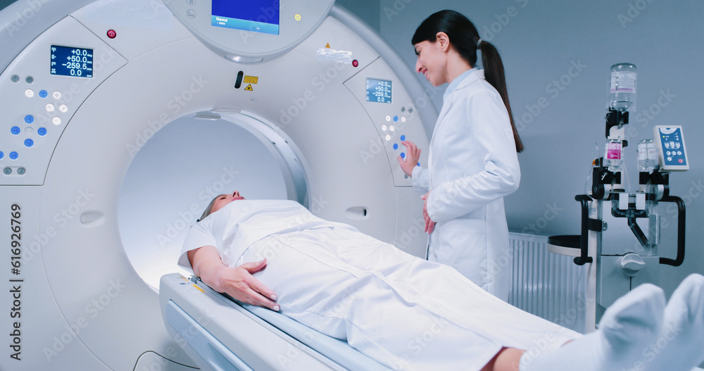 Female medical worker dressed up in gown before MRI procedure. Female doctor is gesturing and
