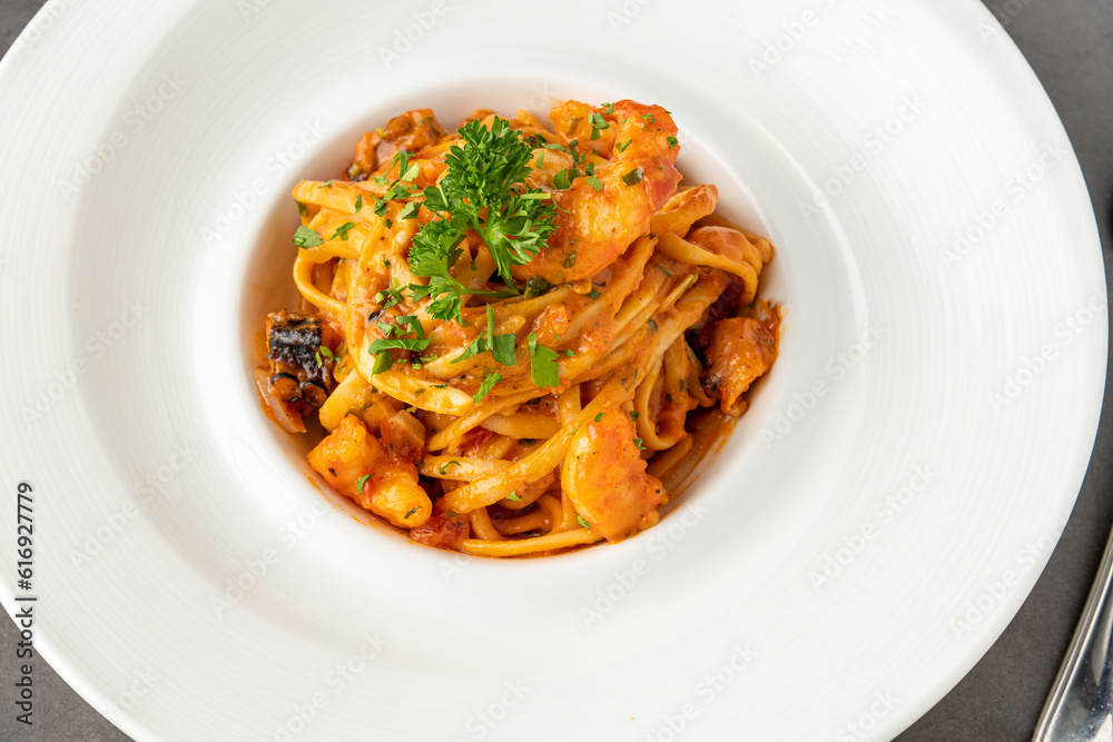 Shrimp spaghetti on white porcelain plate on black stone table