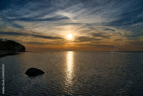 Fototapeta Naklejka Na Ścianę i Meble -  Sunset, small rocks in the water at the shore. Light waves. At the Baltic Sea