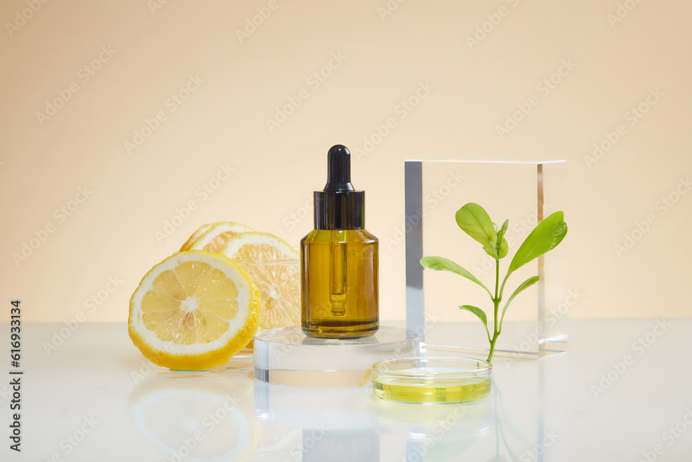 A glass bottle with dropper standing on round podium, some lemon slices, green leaves and petri dish of fluid displayed. Mockup of serum cosmetic product extracted from Lemon (Citrus limon) A glass bottle with dropper standing on round podium, some lemon slices, green leaves and petri dish of fluid displayed. Mockup of serum cosmetic product extracted from Lemon (Citrus limon)