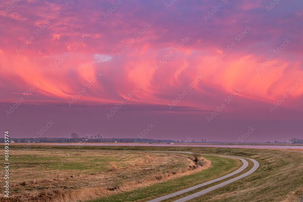 Wolkenformation mit beeindruckenden Farben bei Sonnenuntergang an Bodden vor Zingst an der Ostsee.