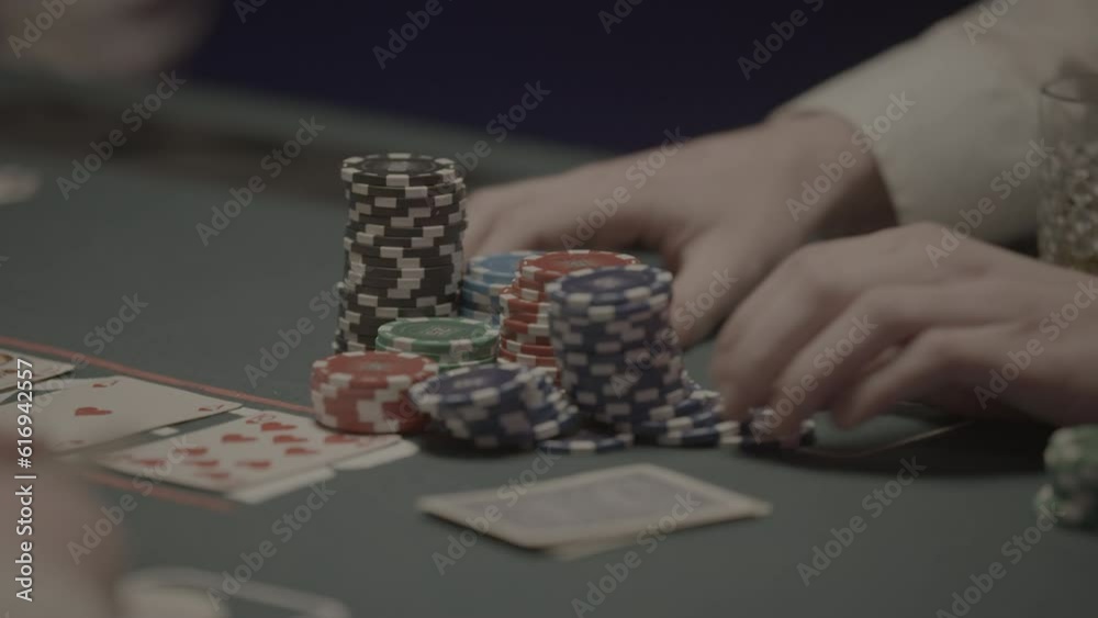 Shot of a person going all in with his pokerchips pushing them to the middle of the table in slowmotion LOG